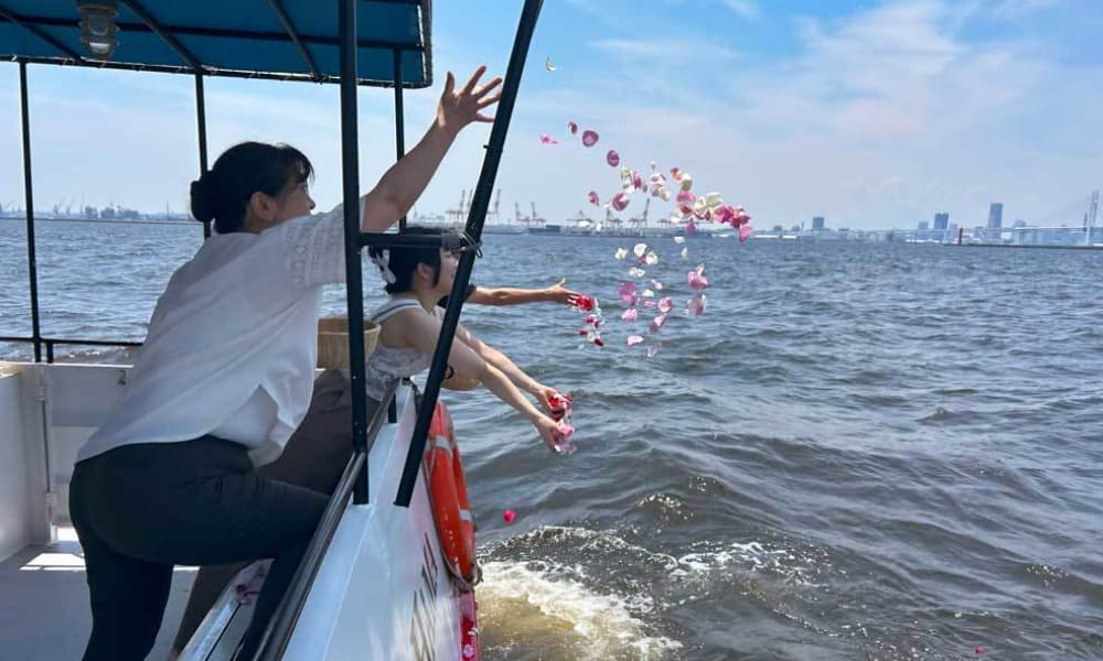 横浜港で家族が花びらを海へ手向ける(遠景にベイブリッジ)